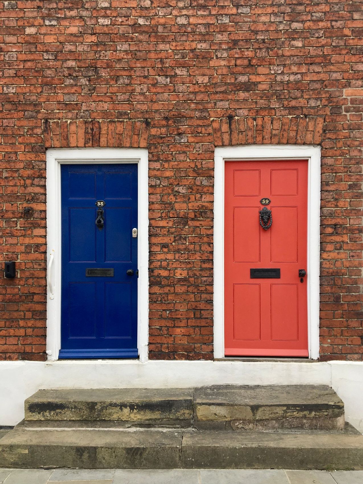 Blue and red front doors set into a traditional brick terrace