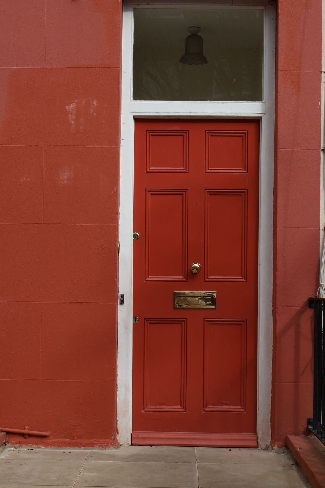 A freshly painted red front door with a brass letterplate