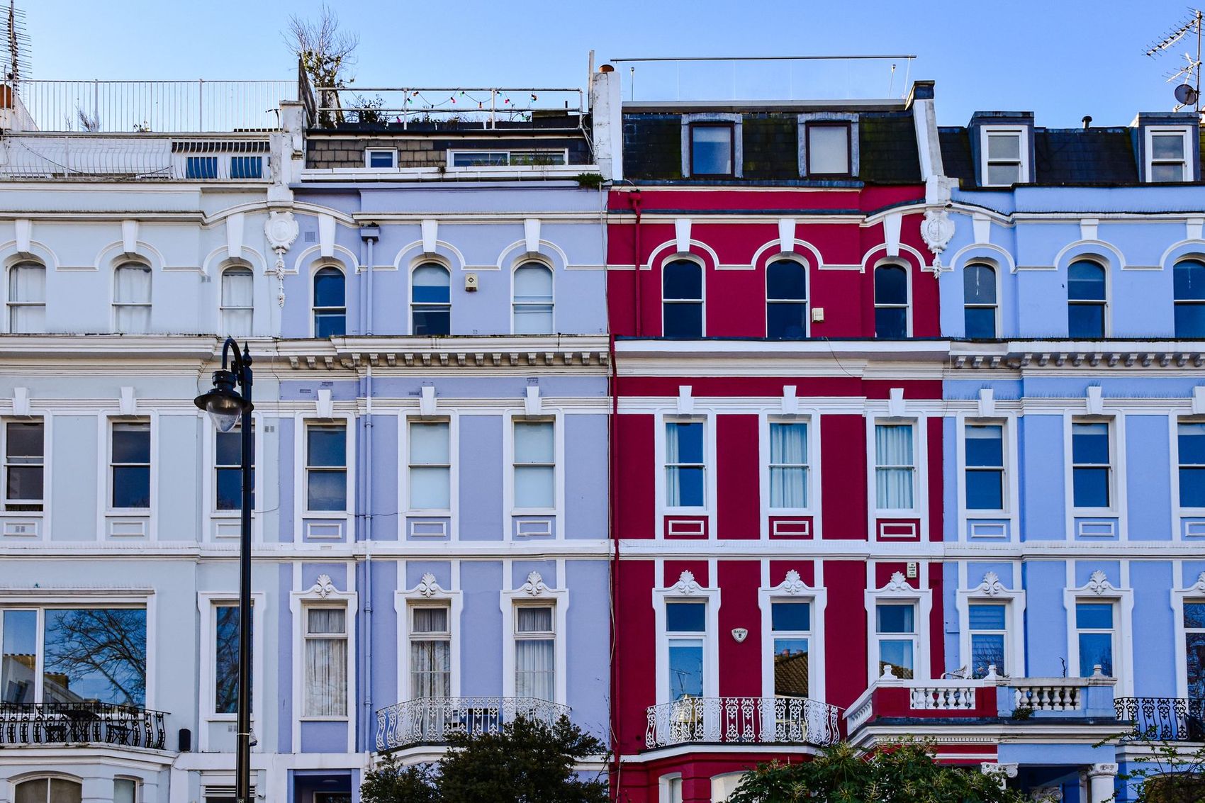 A row of colourful painted London townhouses with sash windows