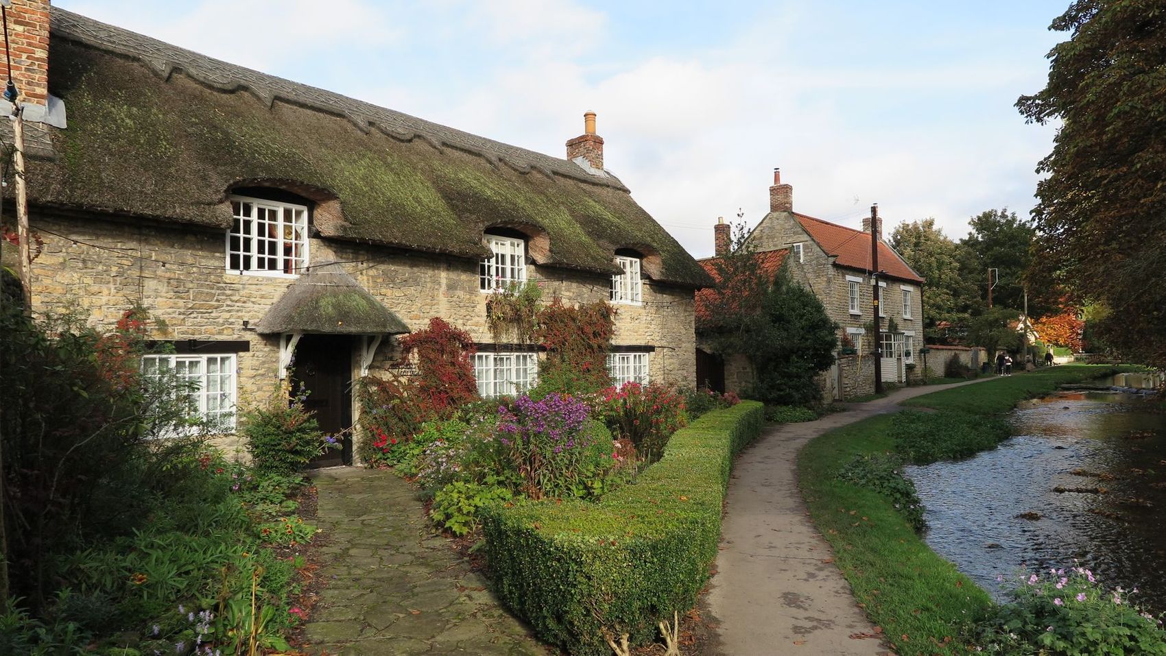 A thatched cottage beside a stream in an English village