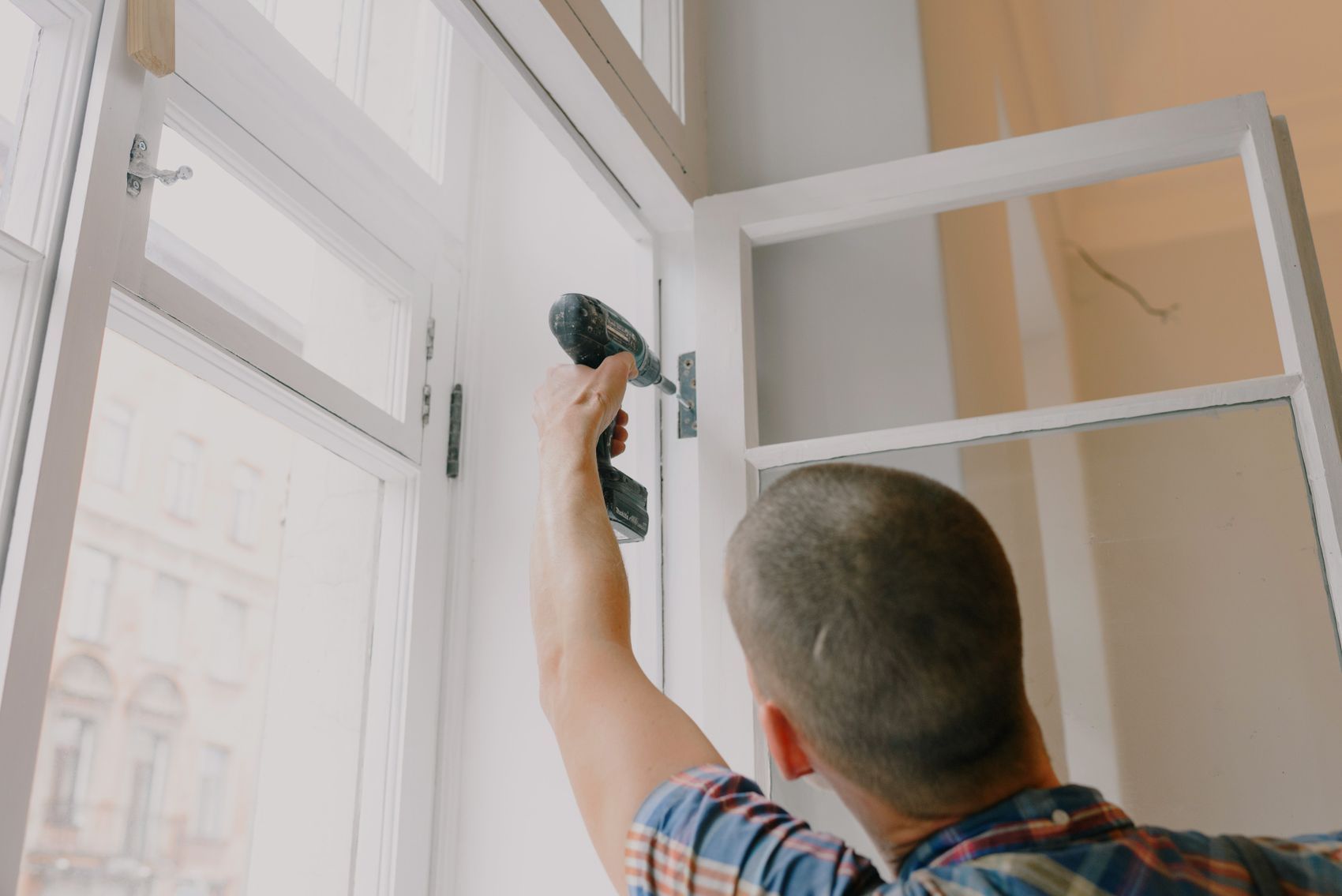A tradesperson adjusting a window hinge