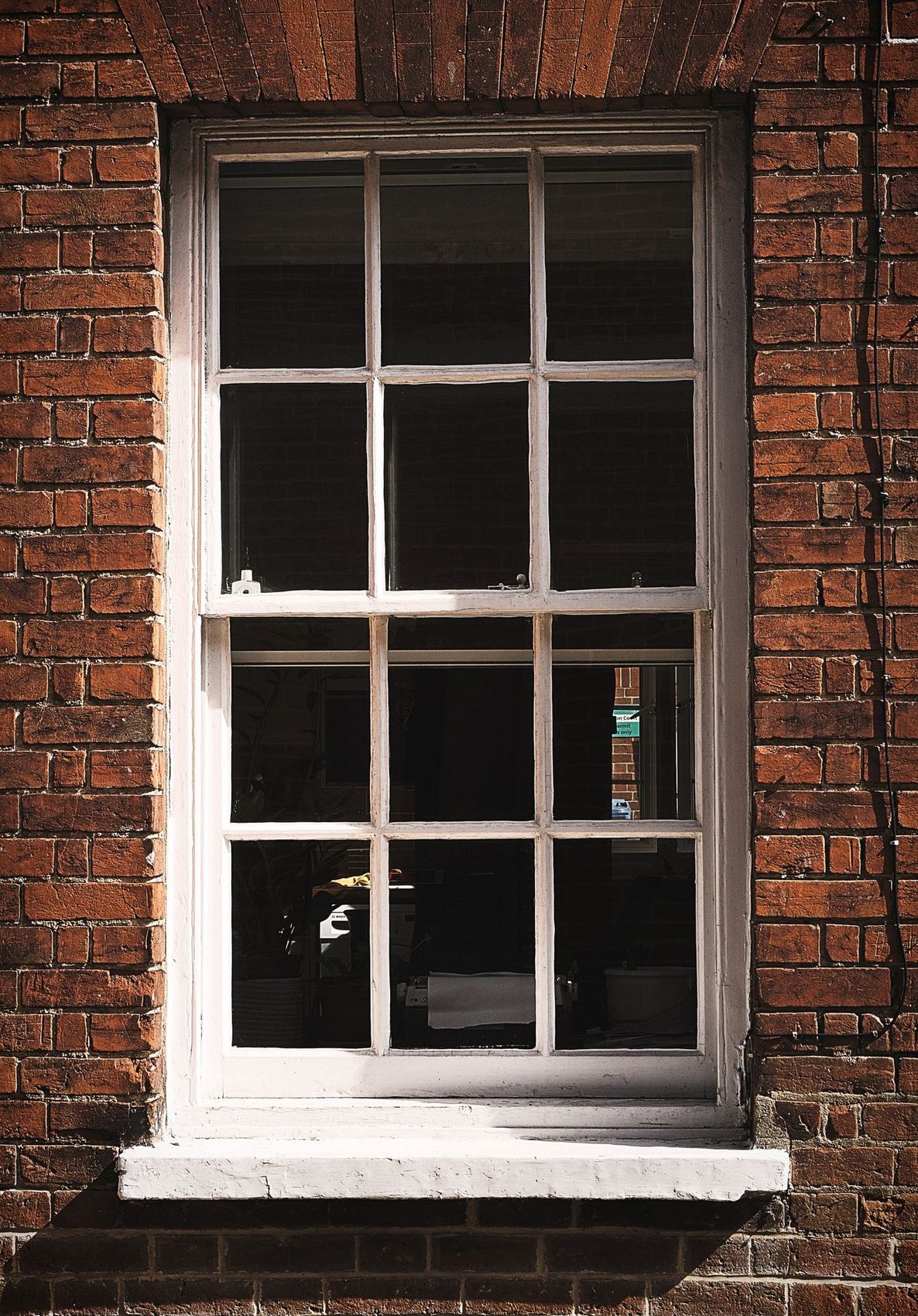 A white sash window set into a red brick wall